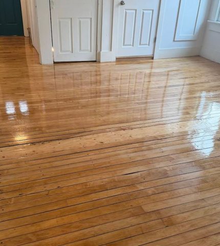 Hardwood floor in a room featuring a white door, creating a warm and inviting atmosphere.